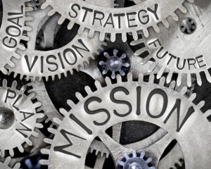 Macro photo of tooth wheel mechanism with MISSION concept related words imprinted on metal surface. 