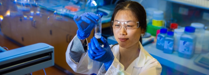 SPSP researcher looking at test tube in lab. 