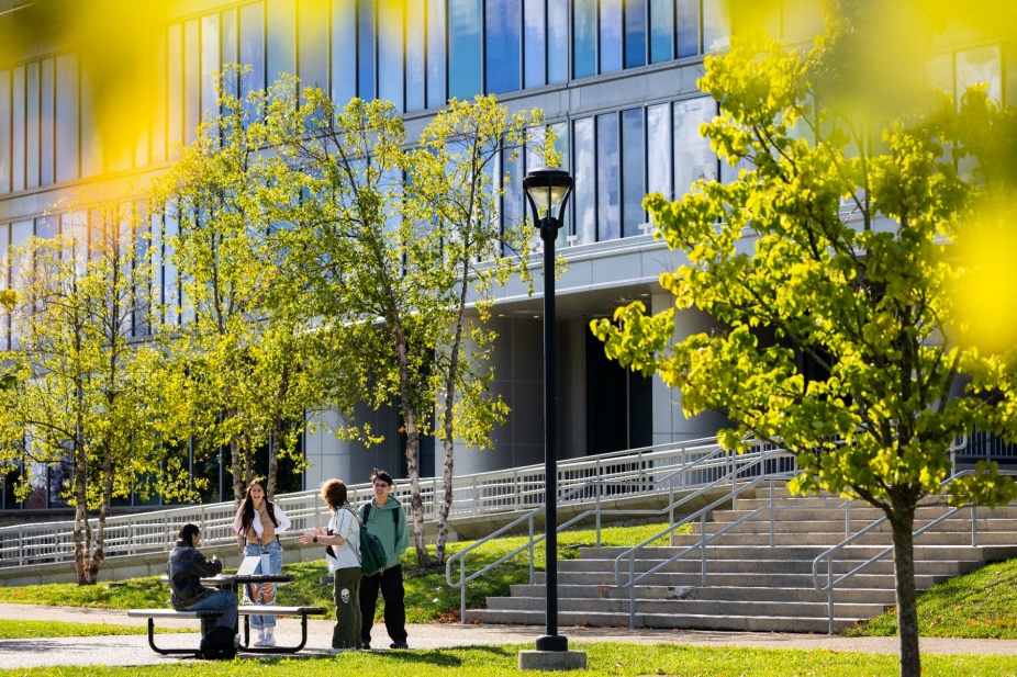 Students gathered at picnic table outside of Pharmacy Building. 
