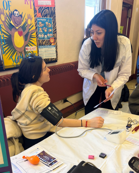 SPPS student assisting community member with blood pressure screening at Cheektowaga Community Health Fair. 